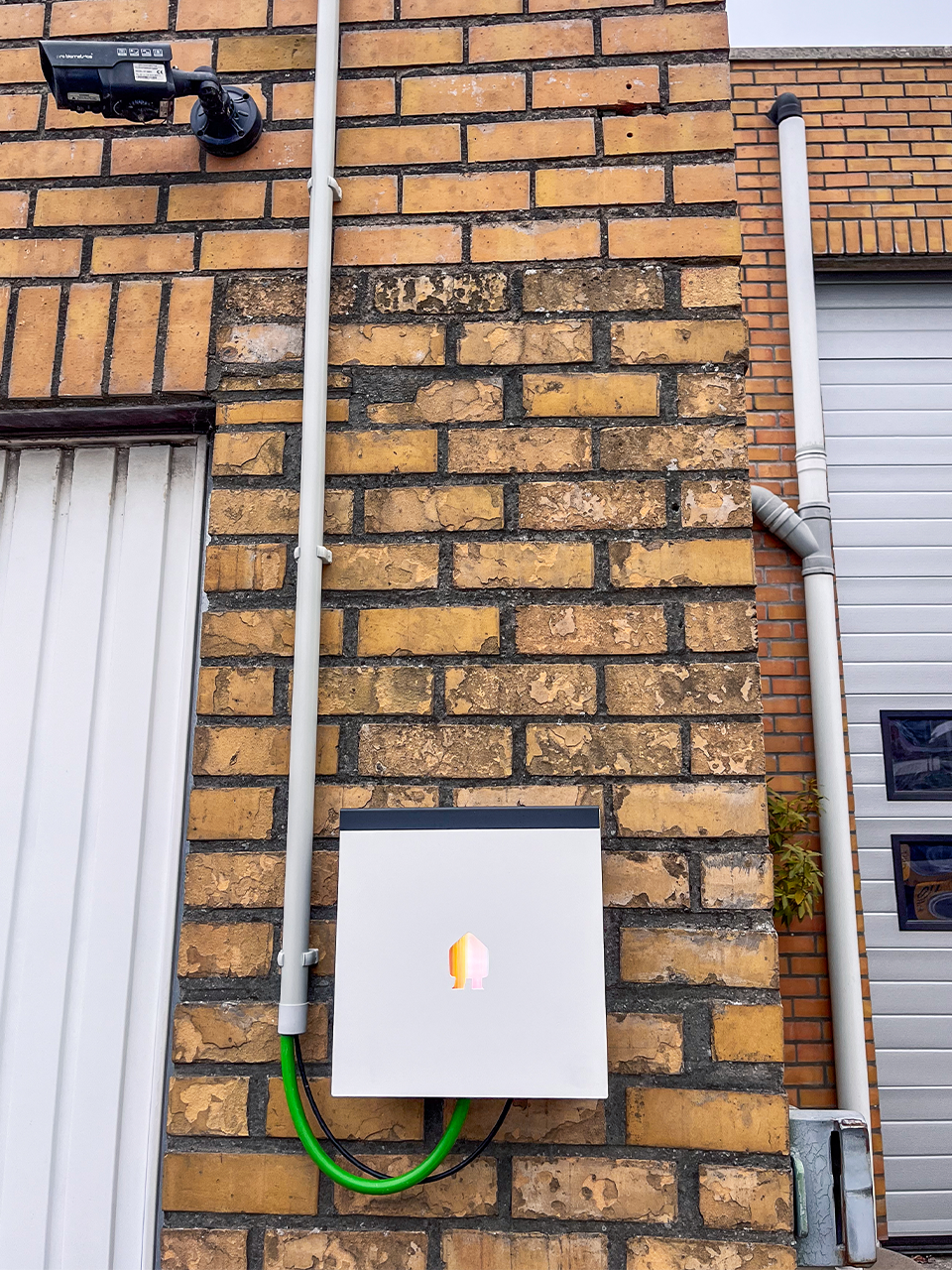Smappee EV Wall Business laadstation aan de achtergevel, met kabeltraject dat via het vals plafond en opbouw langs de zijgevel werd aangelegd.