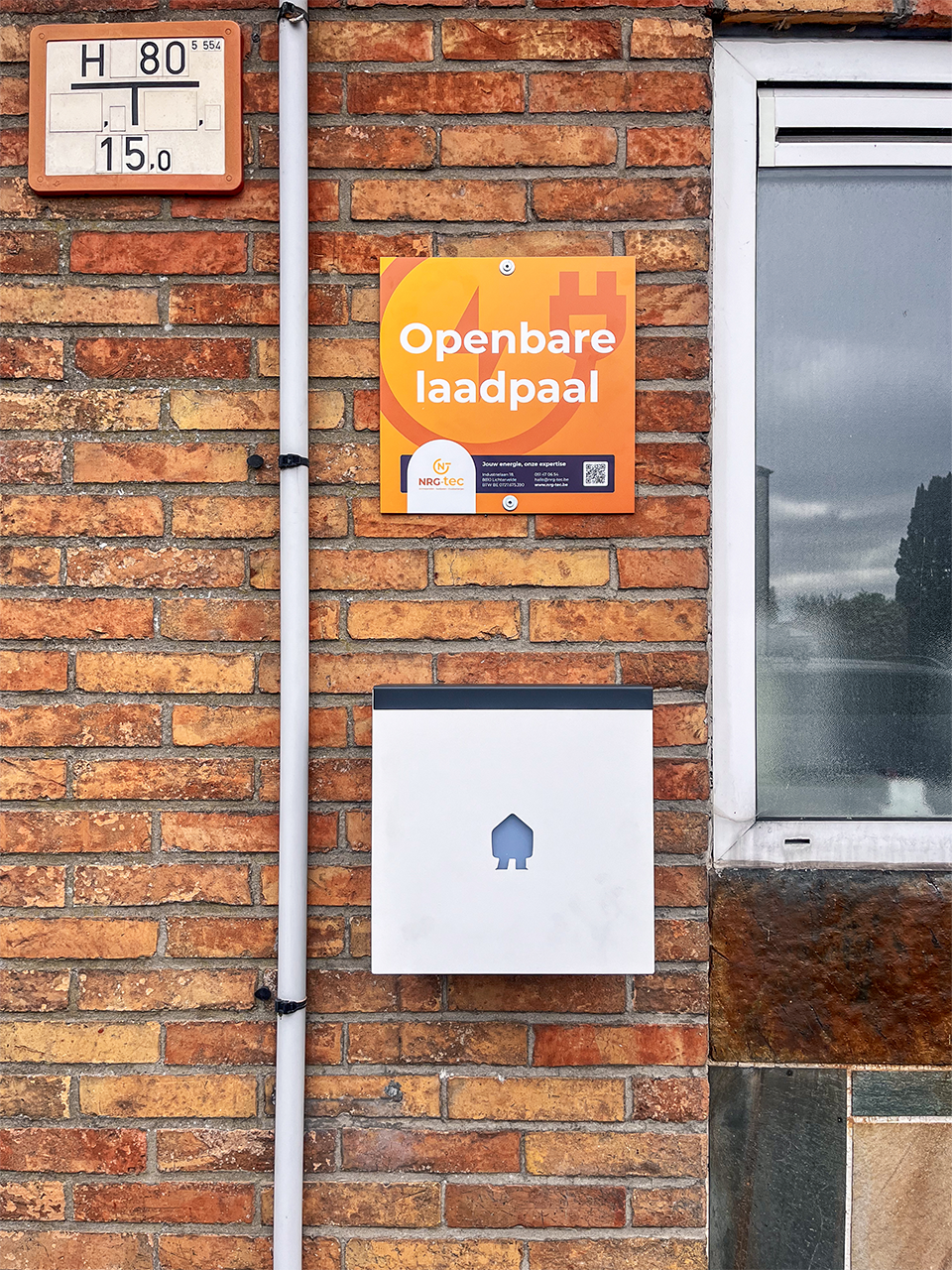 Publieke Smappee EV Wall Business laadpaal aan de voorgevel met duidelijk signalisatiebord ‘Openbare laadpaal’, installatie door NRG-TEC.