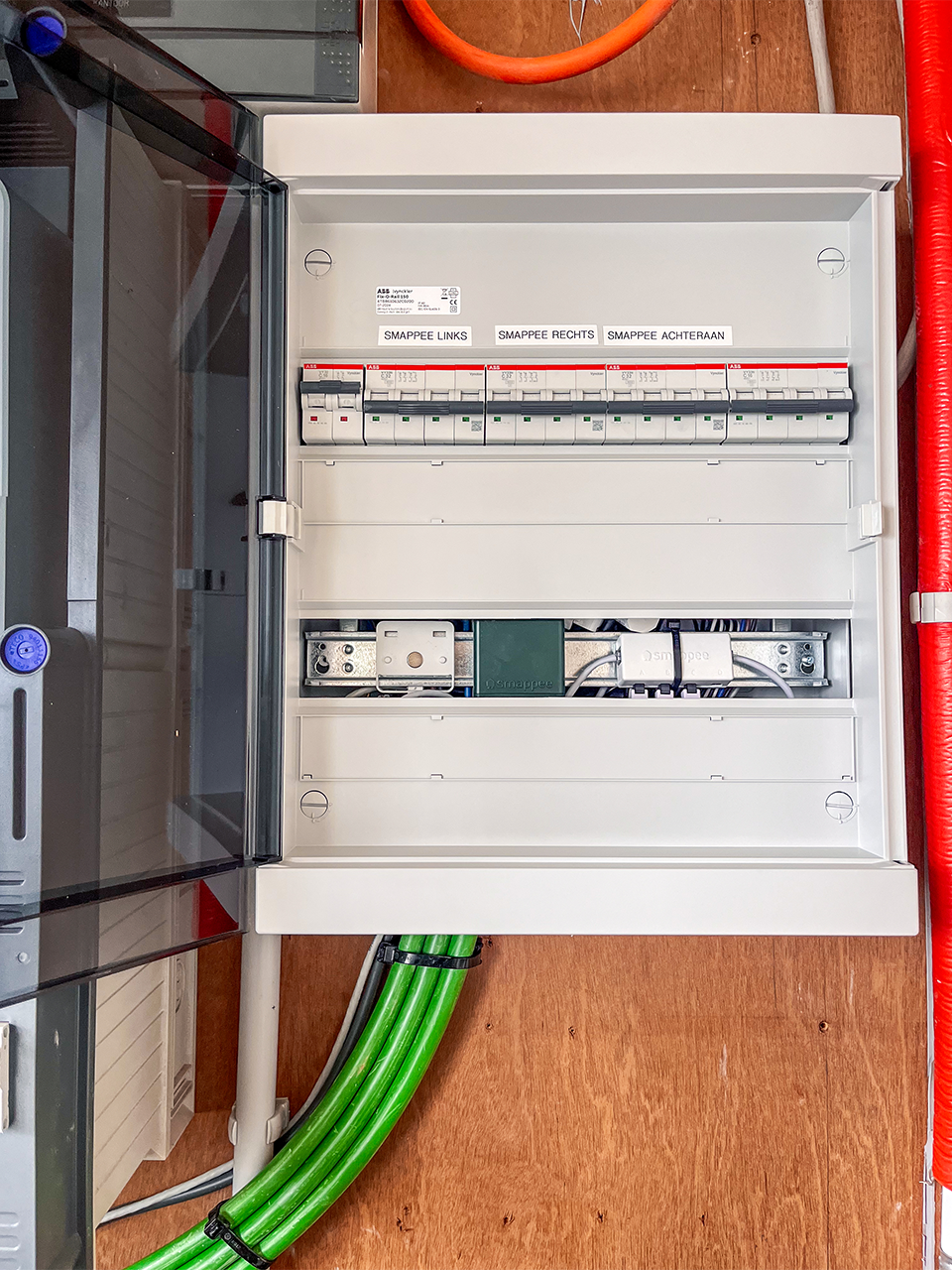 Netjes afgewerkte zekeringkast en bekabeling voor de drie Smappee EV Wall Business laadstations, esthetisch geïntegreerd in de bestaande infrastructuur.